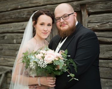 Vihkikuva hirsiseinän edessä