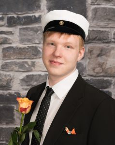 Kiviseinää vasten kuvattu ylioppilas